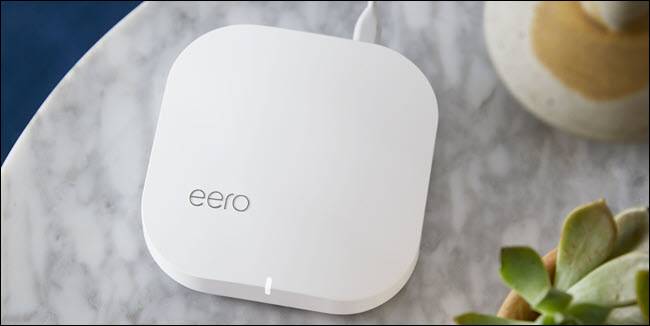 Um roteador Wi-Fi eero em uma mesa ao lado de uma planta.