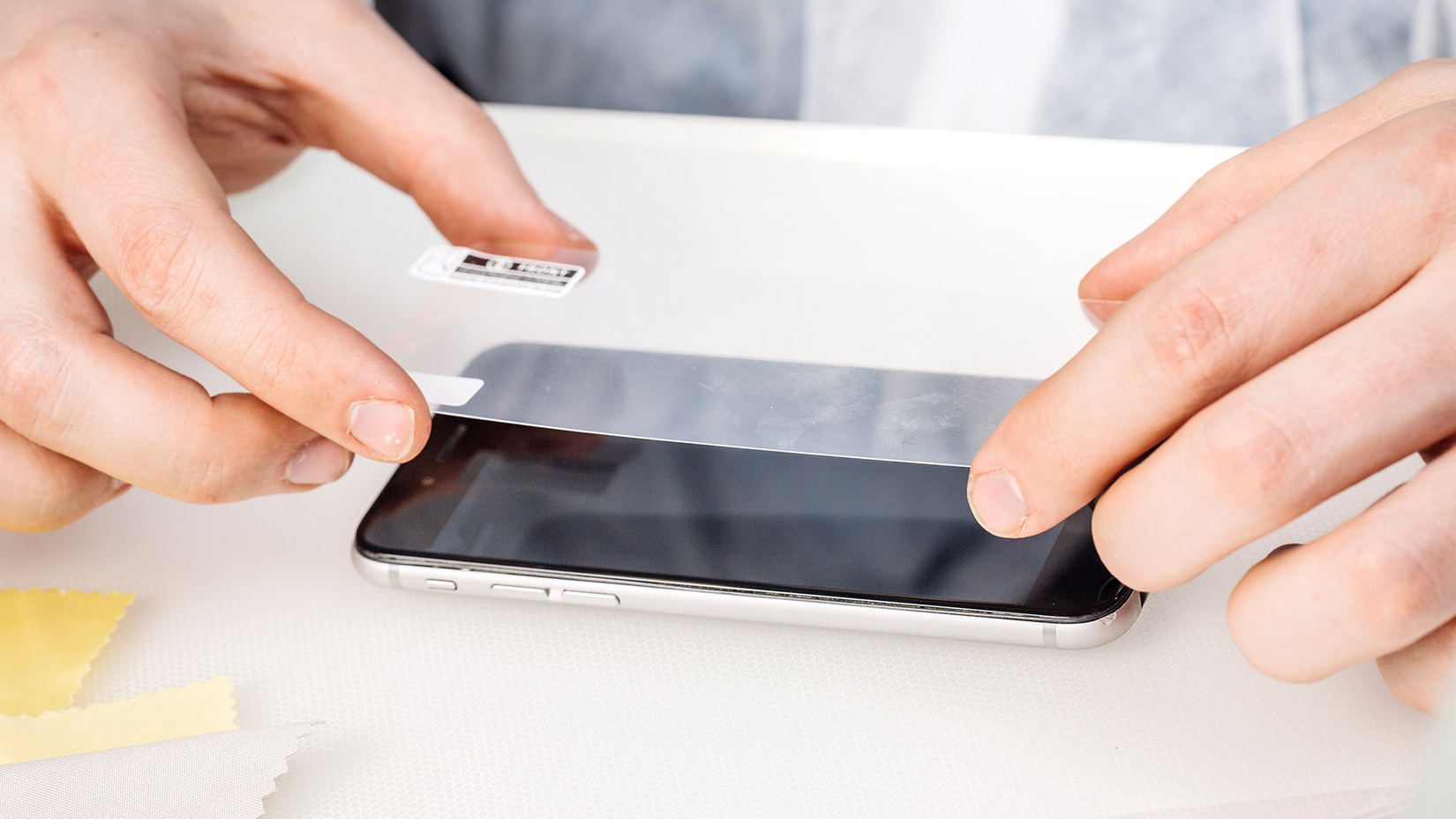 A person applies a plastic screen protector to their phone.