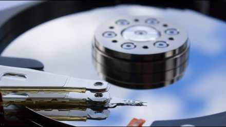 An exposed hard drive platter with the read/write head over top it.