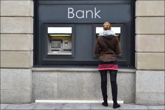 A woman using an outdoor ATM.