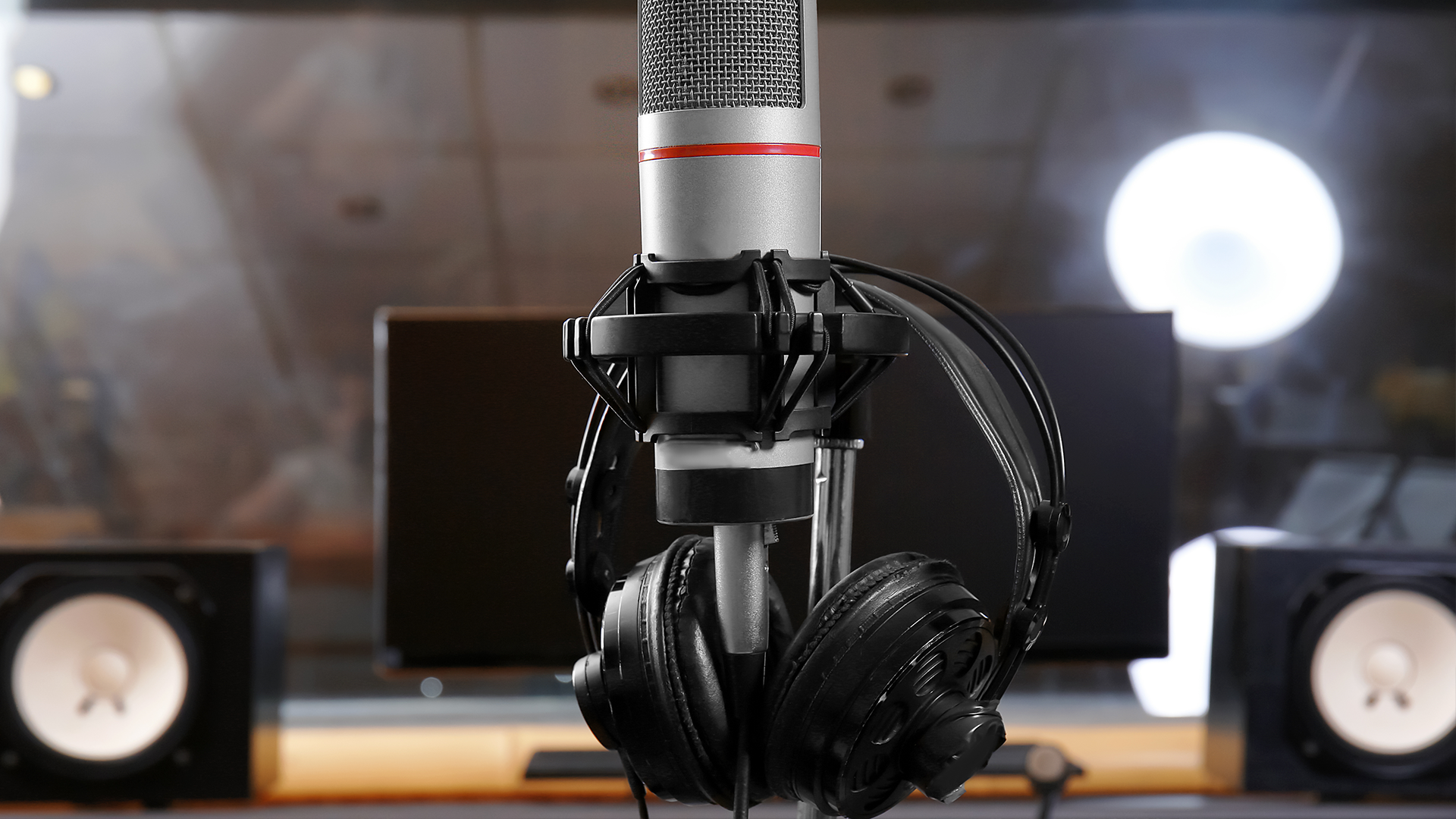 A pair of open-back headphones in a recording studio.