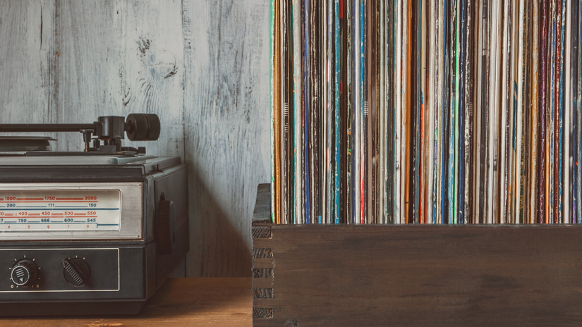 Old vinyl records in a box standing next to a turntable on a table
