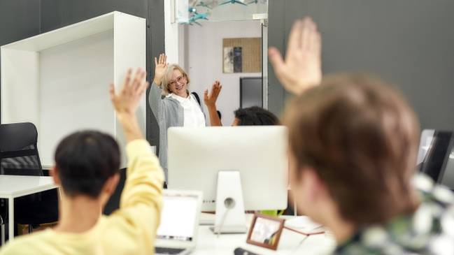 A woman waving goodbye to an office full of people.