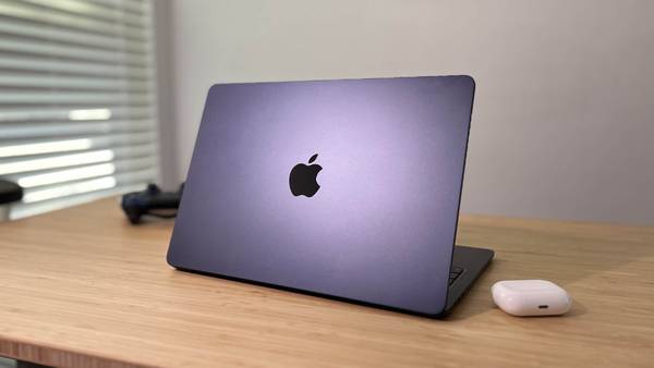 Apple MacBook Air M2 resting on desk next to AirPods Pro and PS4 controller