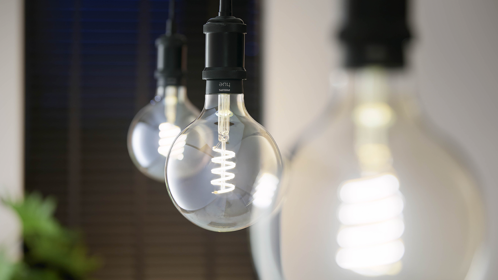 Three Philips Hue G25 filament bulbs hanging in a row.