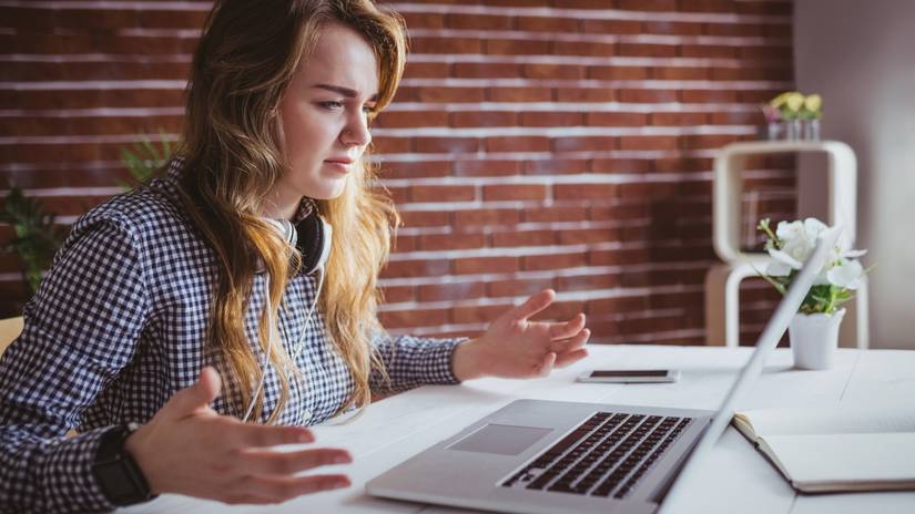 Young woman with her hands up in frustration with a Macbook laptop