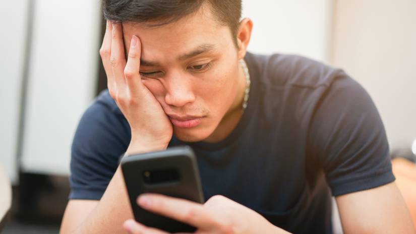 Person scrolling on a phone with a bored look on their face.