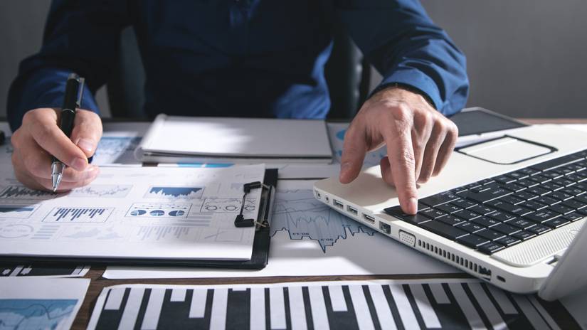 Close-up of financial documents spread on desk near laptop.
