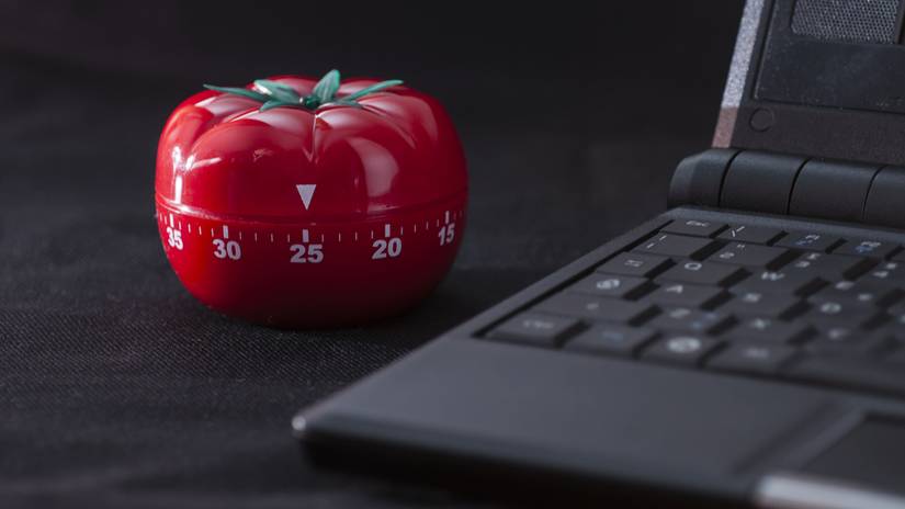 A classic Pomodoro timer next to a laptop