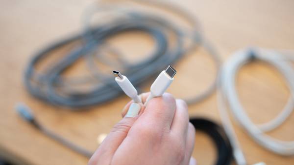 A bunch of USB-C cables on a table and in a person's hand