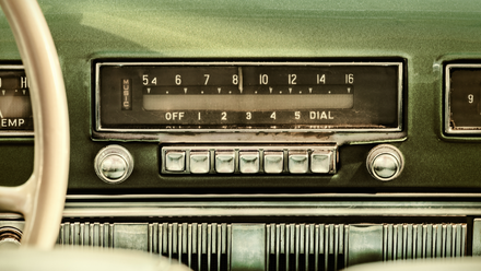 Retro styled image of an old car radio inside a green classic car.