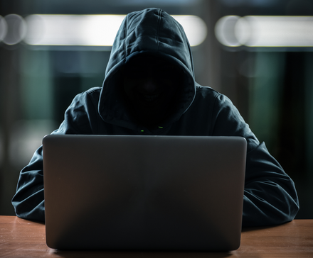 Hacker in front of his computer with a dark face.
