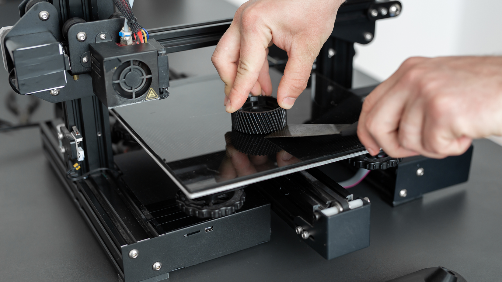Someone peeling a boat of a 3d printer bed with a spatula