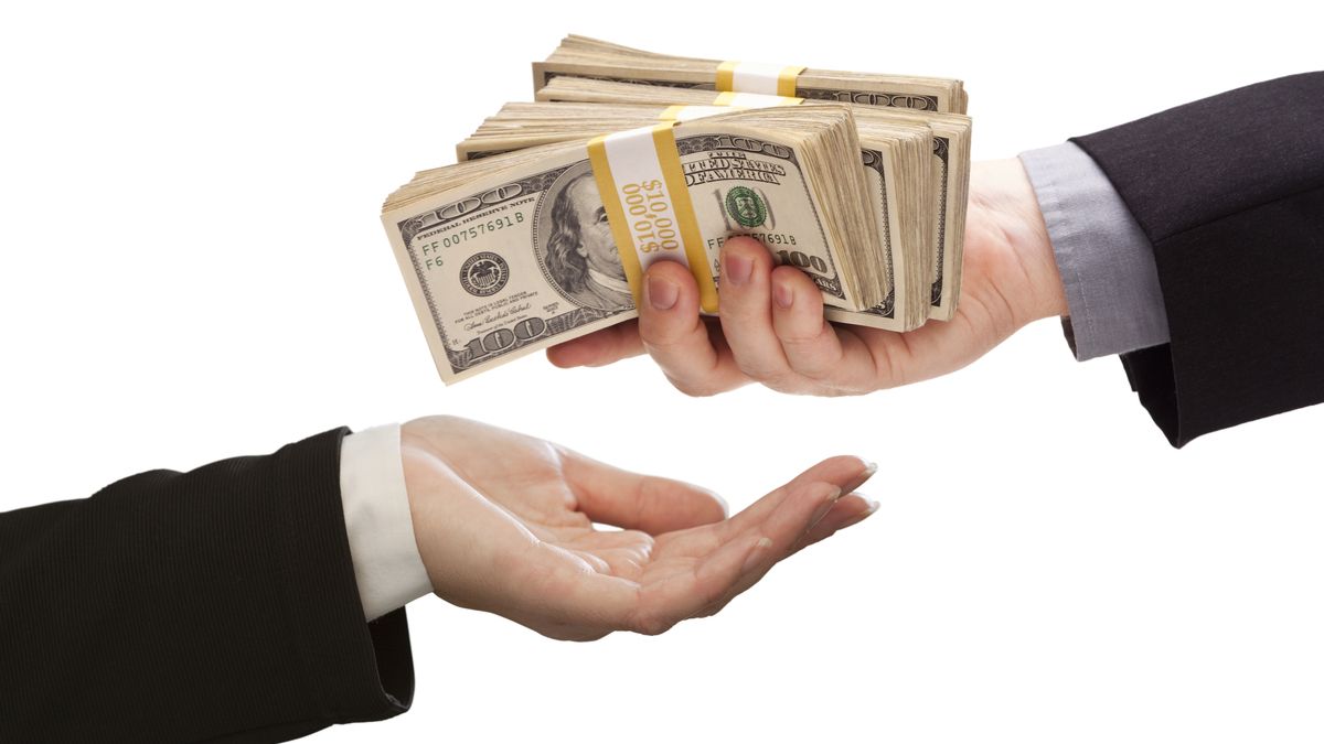 A person handing over a large stack of cash.