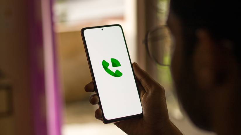 Person holding up a smartphone with the Google Voice app icon on display.
