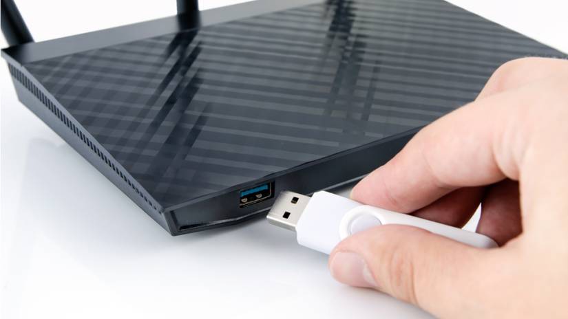 A man inserting a USB drive into an internet router.