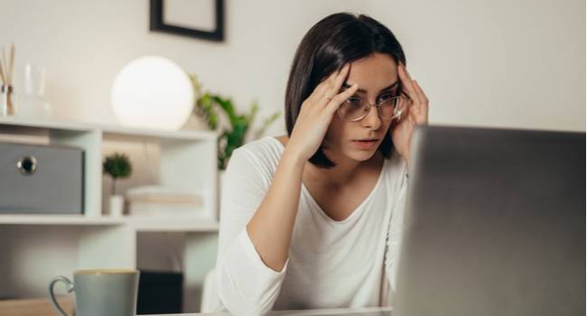 Woman looking at a laptop with a stressed expression.