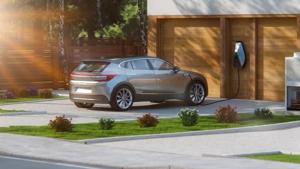 An electric car parked at a home charging in the driveway.