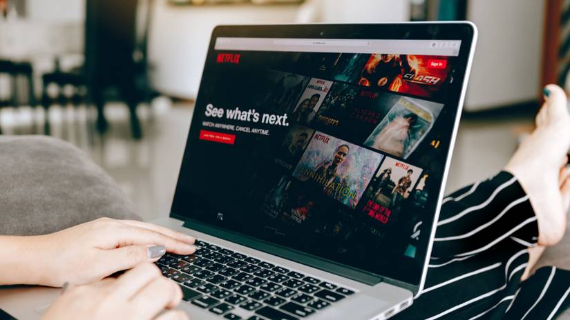 Laptop on a person's lap, with the Netflix website visible in a browser.