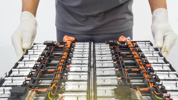 Technician wearing gloves and handling an electric car battery