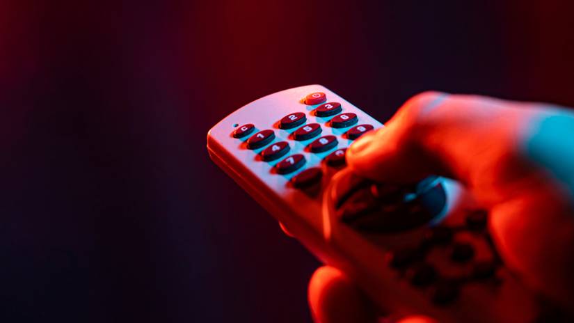 Uma mão pressionando um botão em um controle remoto de TV IR.