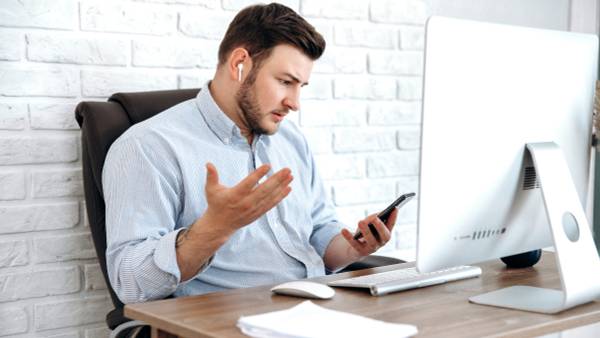 Man using AirPods and looking at his iPhone in surprise