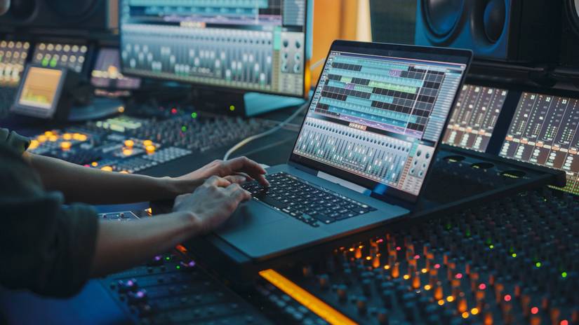Person working on a laptop in a modern music studio.