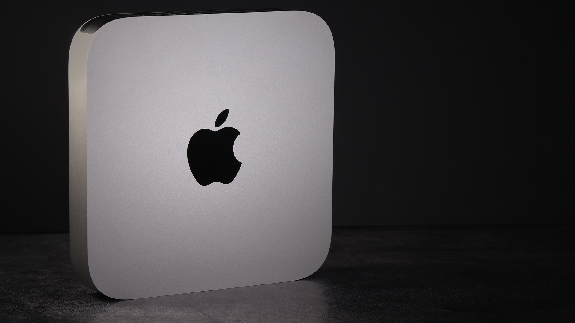 Mac Mini stands on its side against a dark background.