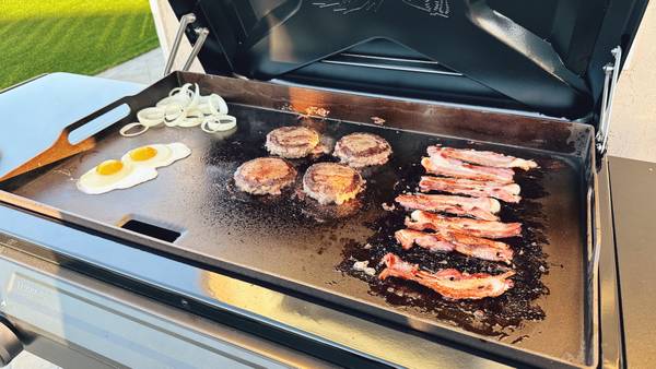 Eggs, burgers, and bacon cooking on the Traeger Flatrock grill