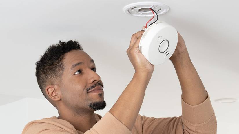 A person setting up Kidde smart smoke detector.