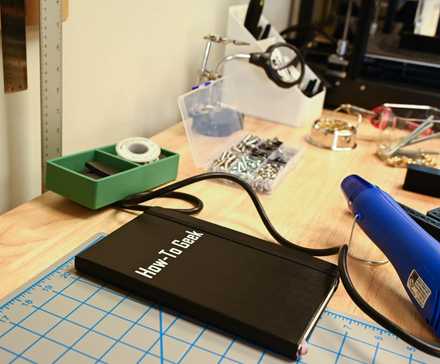 A How To Geek Notebook on a workbench with tools