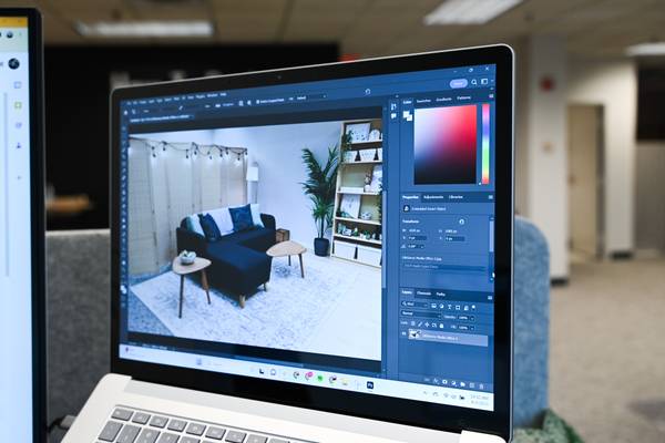 Laptop computer screen with Adobe PhotoShop open and a photo of a living room being edited.