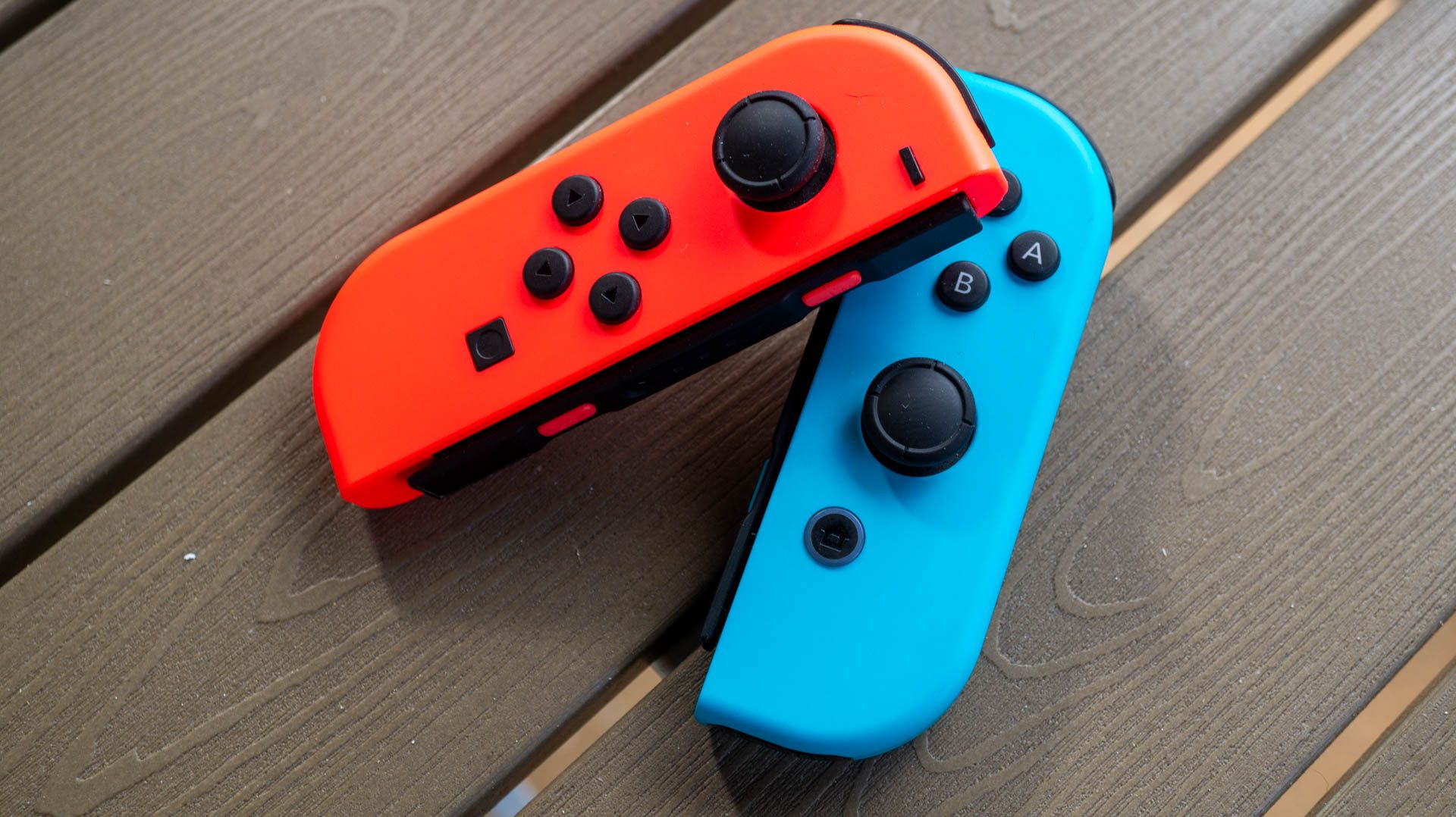 Red and blue Nintendo Switch Joy Cons on a wooden table.