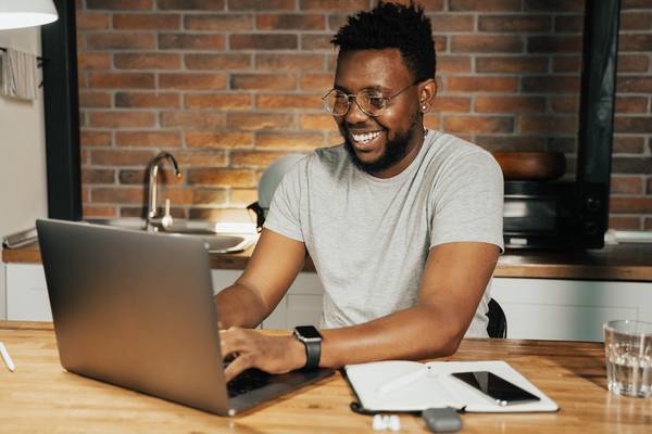 A young man sits at a desk working on a laptop