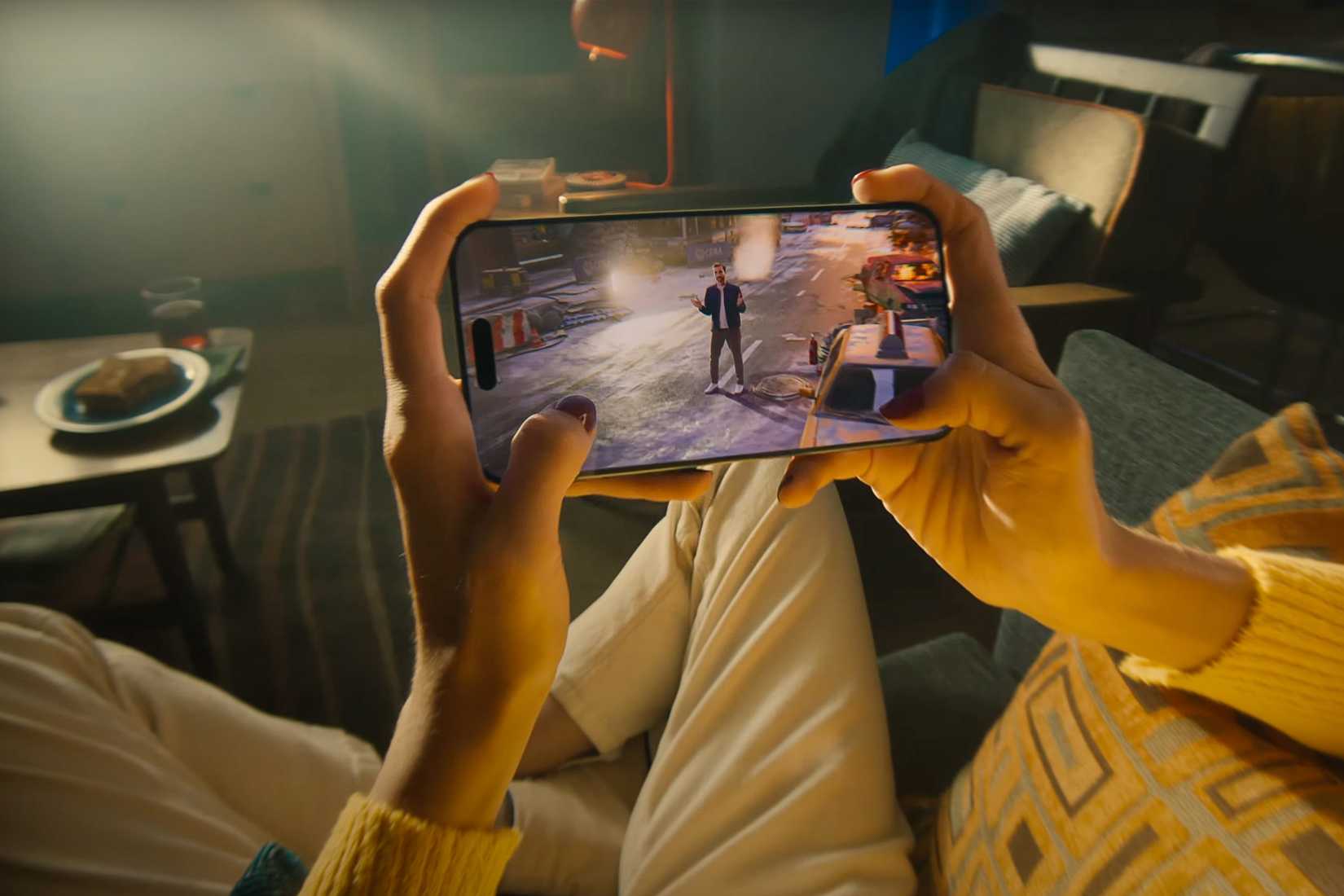 A person holding an iPhone 15 Pro and playing video games.