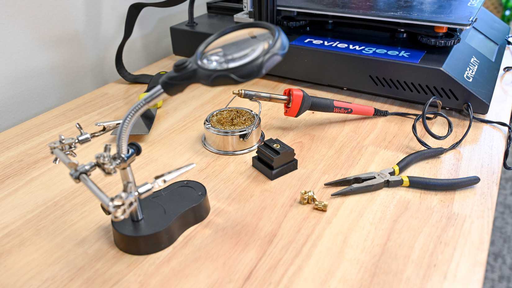 A soldering iron in front of a 3D printer