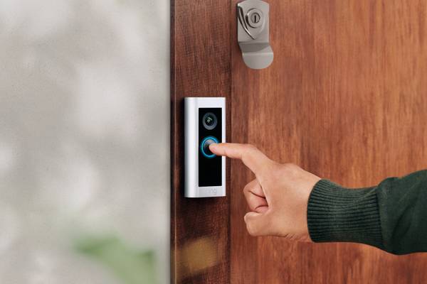 A person pressing the button on a Ring Pro 2 doorbell.