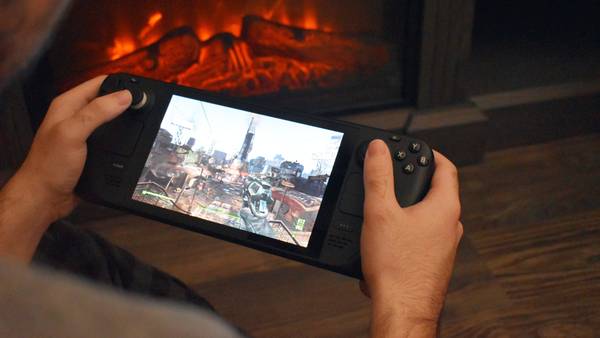 Person's hands holding the Steam Deck and playing a game, with a fireplace in the background.