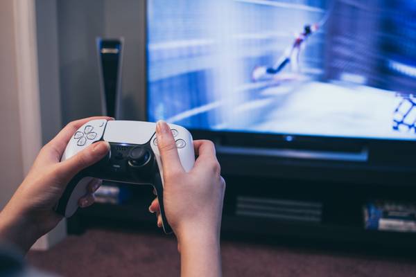 Holding a PS5 DualSense controller in front of a TV showing Spider-Man.