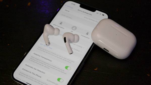 AirPods Pro 2 resting on iPhone with AirPods settings on screen