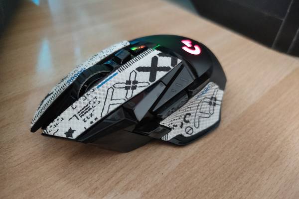 A side view of the Logitech G502 Lightspeed wireless gaming mouse on a wooden desk.