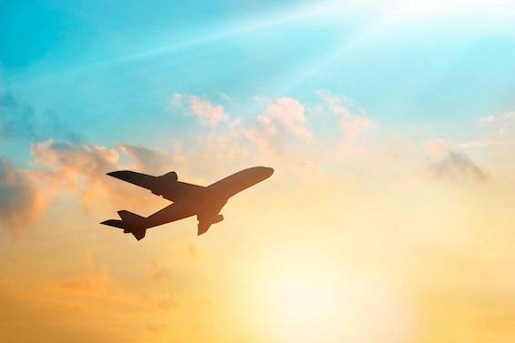 Airplane in a pastel cloud orange sky. 