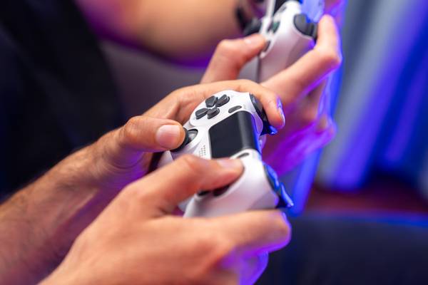 Person holding a PlayStation 4 DualShock 4 controller in white.