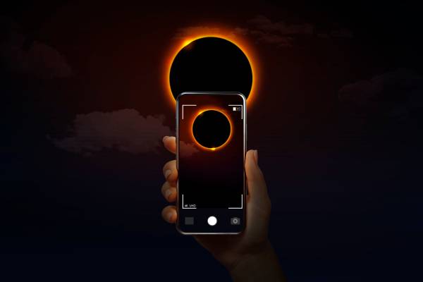 A hand holding a phone taking a picture of the Eclipse
