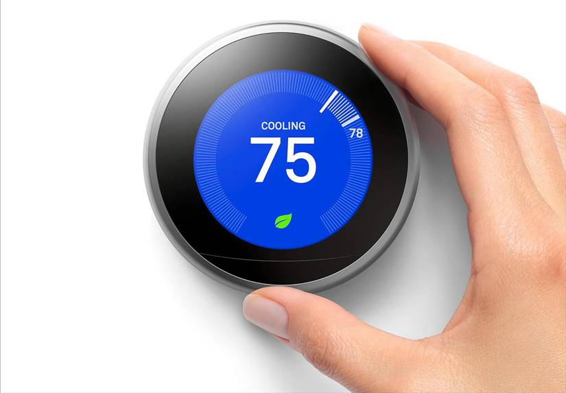 Hand turning Google Nest thermostat to set a temperature.
