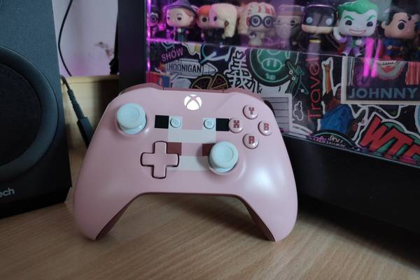 A special edition Xbox One Minecraft Pig controller leaning against a computer.