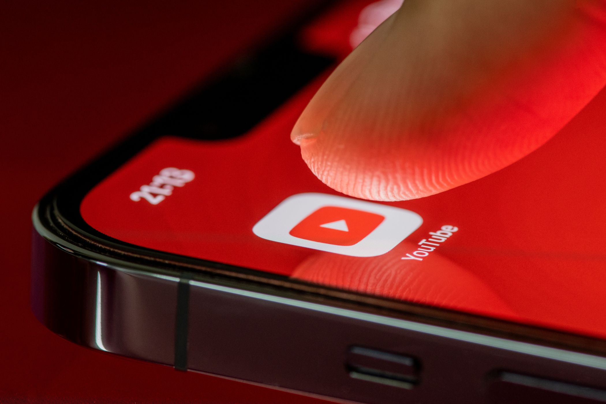 A finger tapping the YouTube app on an iPhone.
