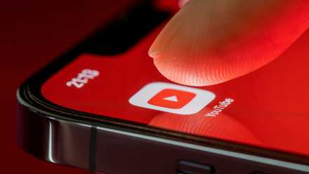 Использование мобильного приложения YouTube на смартфоне A finger tapping the YouTube app on an iPhone.