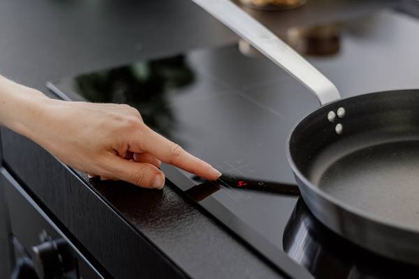 A woman pressing a touch button on an induction hob.