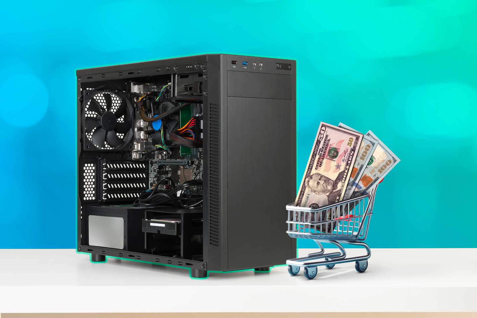 A computer case and a miniature shopping cart with several dollar bills.